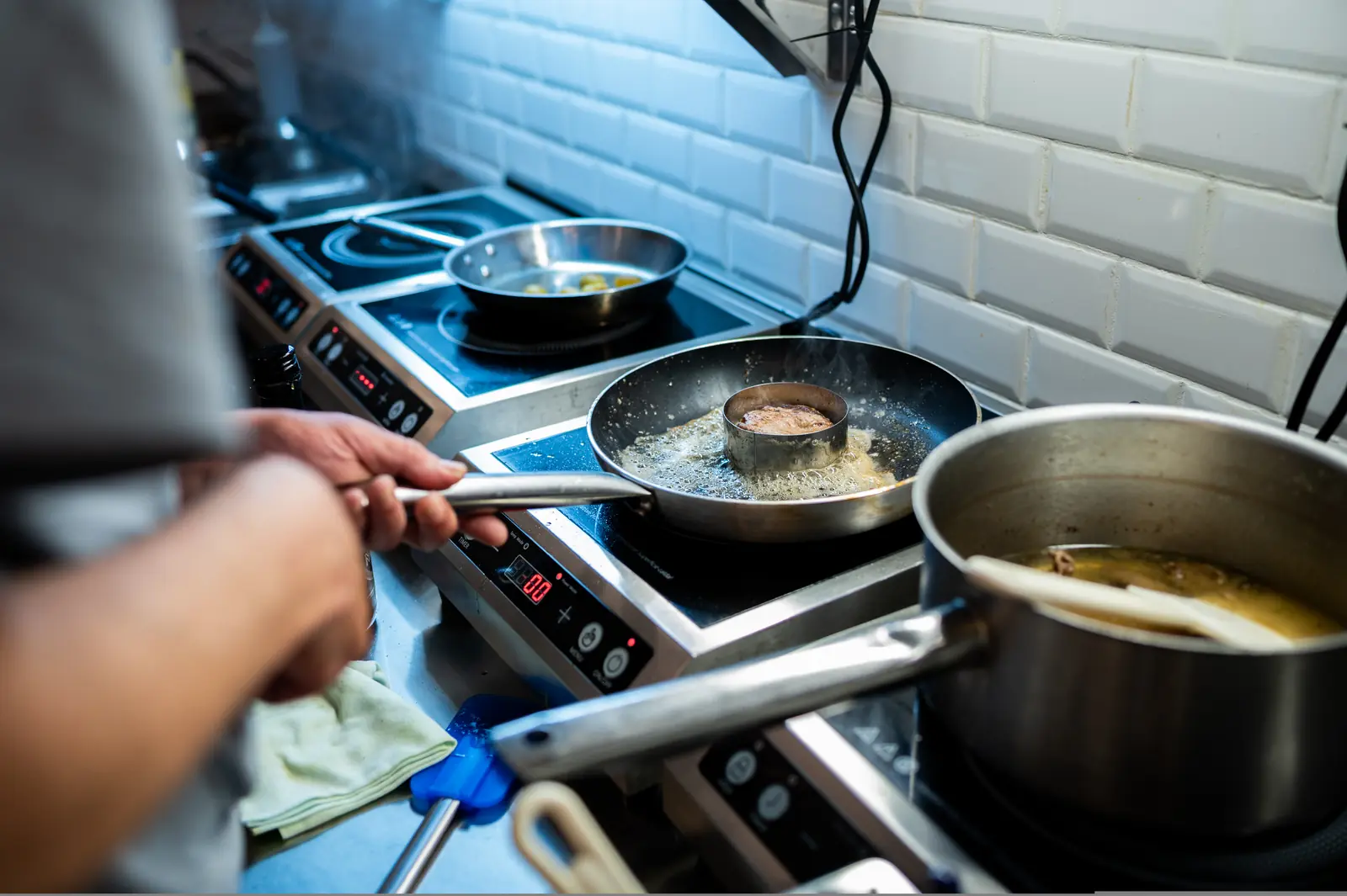 Cucina a vista con primi piatti e padelle al fuoco